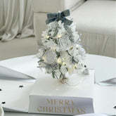 Celebrate the holidays with the Bow Christmas Tree Eternal Flower Arrangement, featuring red roses, hydrangeas, and gold accents. A luxury festive décor piece perfect for gifting or brightening your Christmas home with timeless elegance.