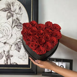 A luxurious heart box filled with 13 or 20 handcrafted forever roses, featuring a Parisian black hat-box design with gold detailing. Bloom 3+ years.