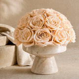 Floral Isle luxury champagne preserved roses arranged in an organic modern travertine stone vessel centerpiece, side view.
