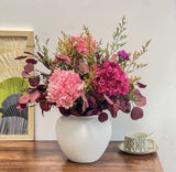 A luxury preserved flower arrangement featuring preserved hydrangeas, eucalyptus, and rich pink-burgundy hues in a matte ceramic vase—perfect for modern décor, birthdays, weddings, and lasting gifts.
