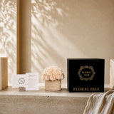 Full unboxing set of Floral Isle champagne eternal roses featuring the travertine vase, high-end black gift box, and elegant care cards.