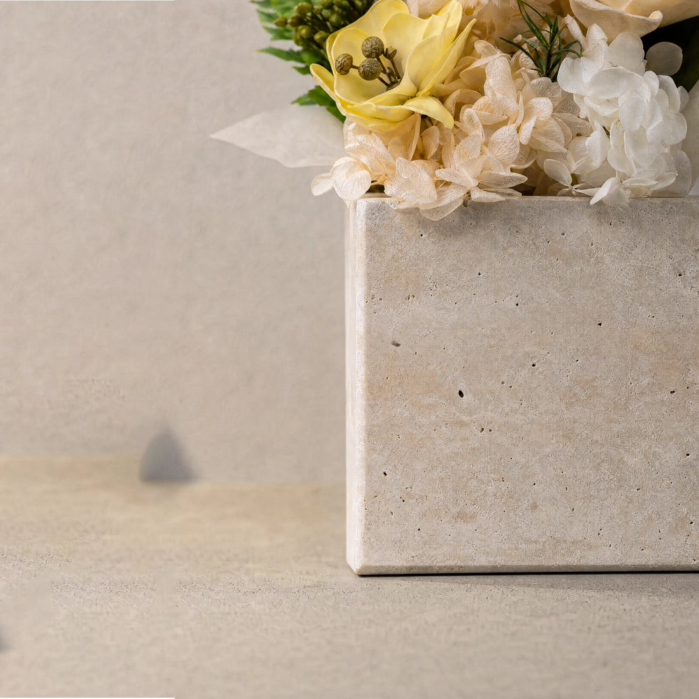 Macro shot of raw yellow travertine rock showing authentic weathered cavities and delicate everlasting flower stems.