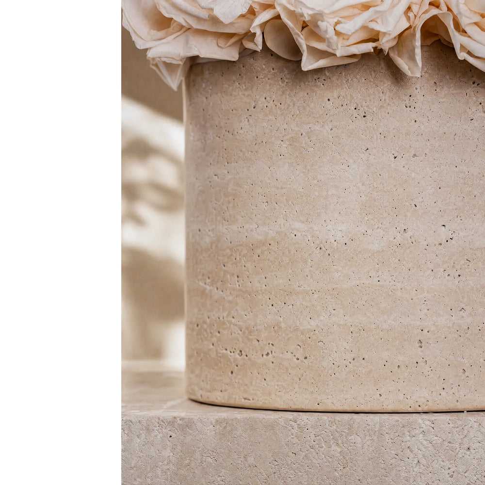 Macro close-up shot of the porous, natural travertine stone vase surface highlighting the organic luxury texture.