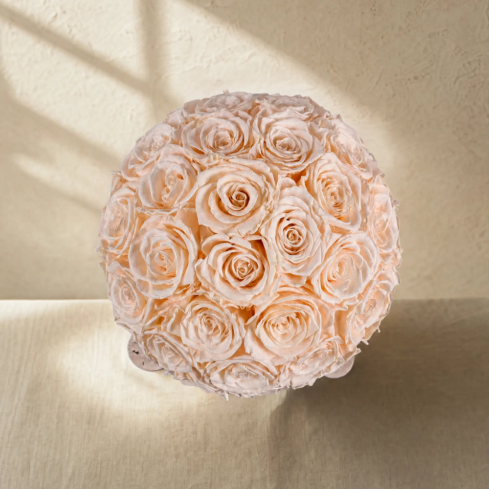 Top-down bird's-eye view showing the dense, flawless spherical arrangement of blooming champagne preserved roses.